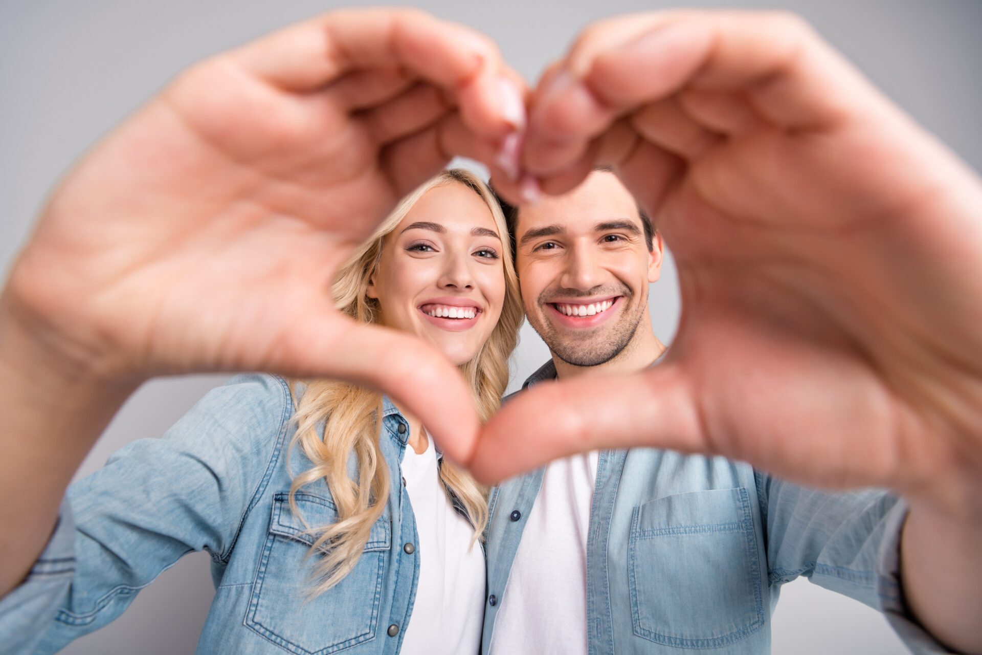 Photo of young couple happy positive smile show fingers heart figure love romantic isolated over grey color background.